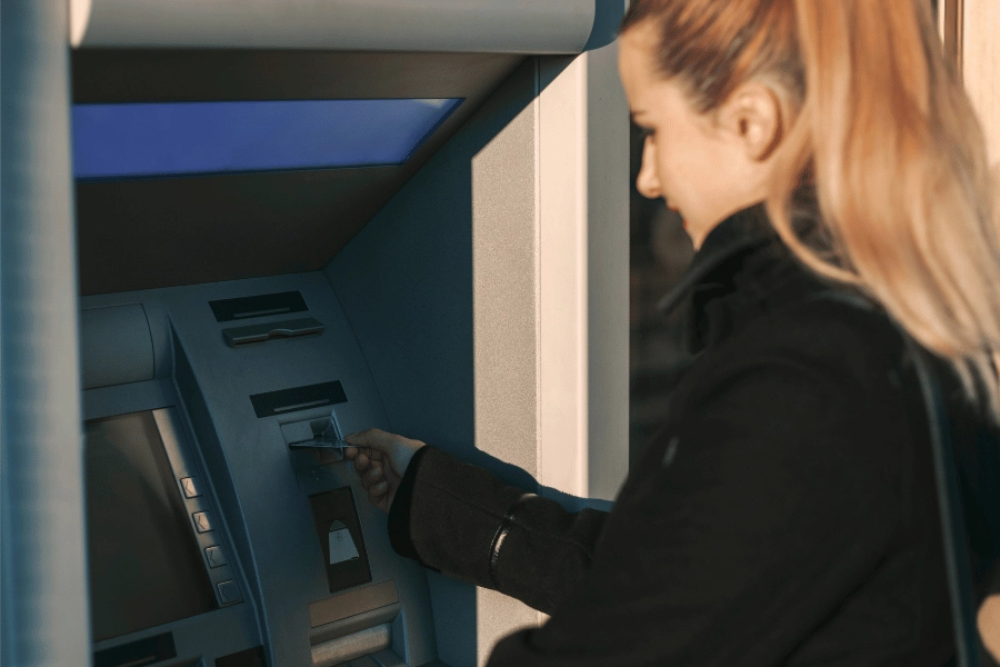 Woman putting debit card into a cash machine