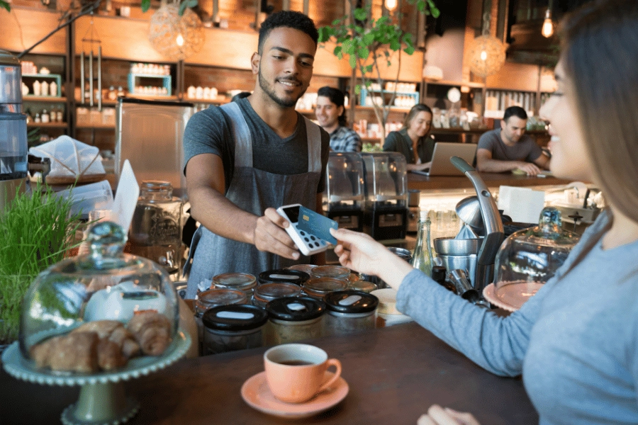 Cafe worker accepting a contactless payment for a cup of coffee