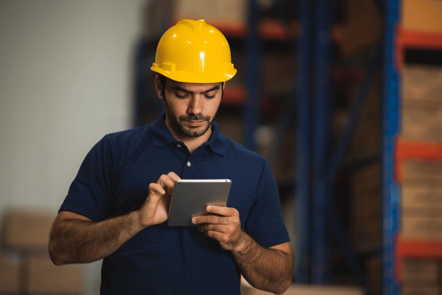 Warehouse worker in a hard hat using a tablet