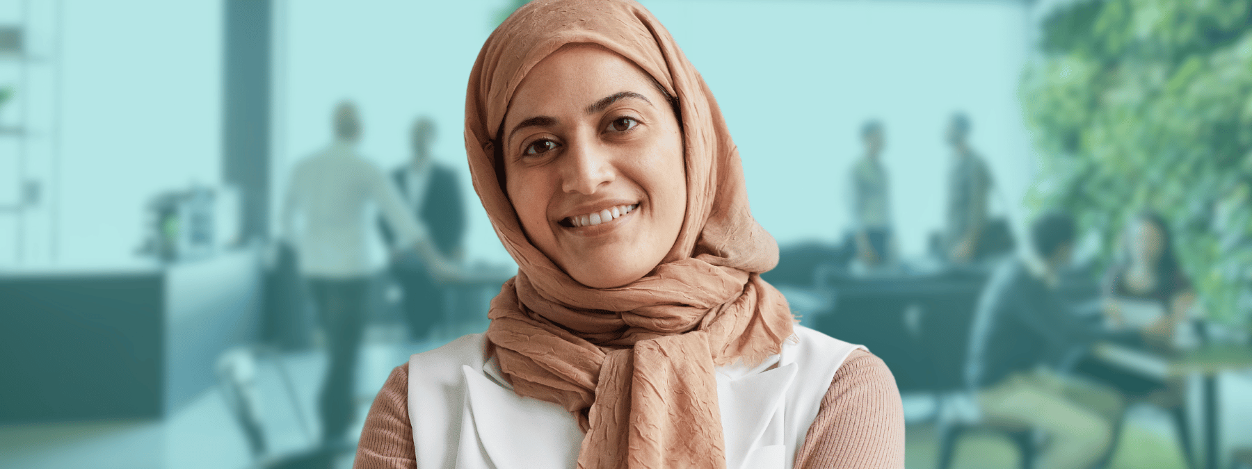 Woman wearing a hijab with a background of an office environment